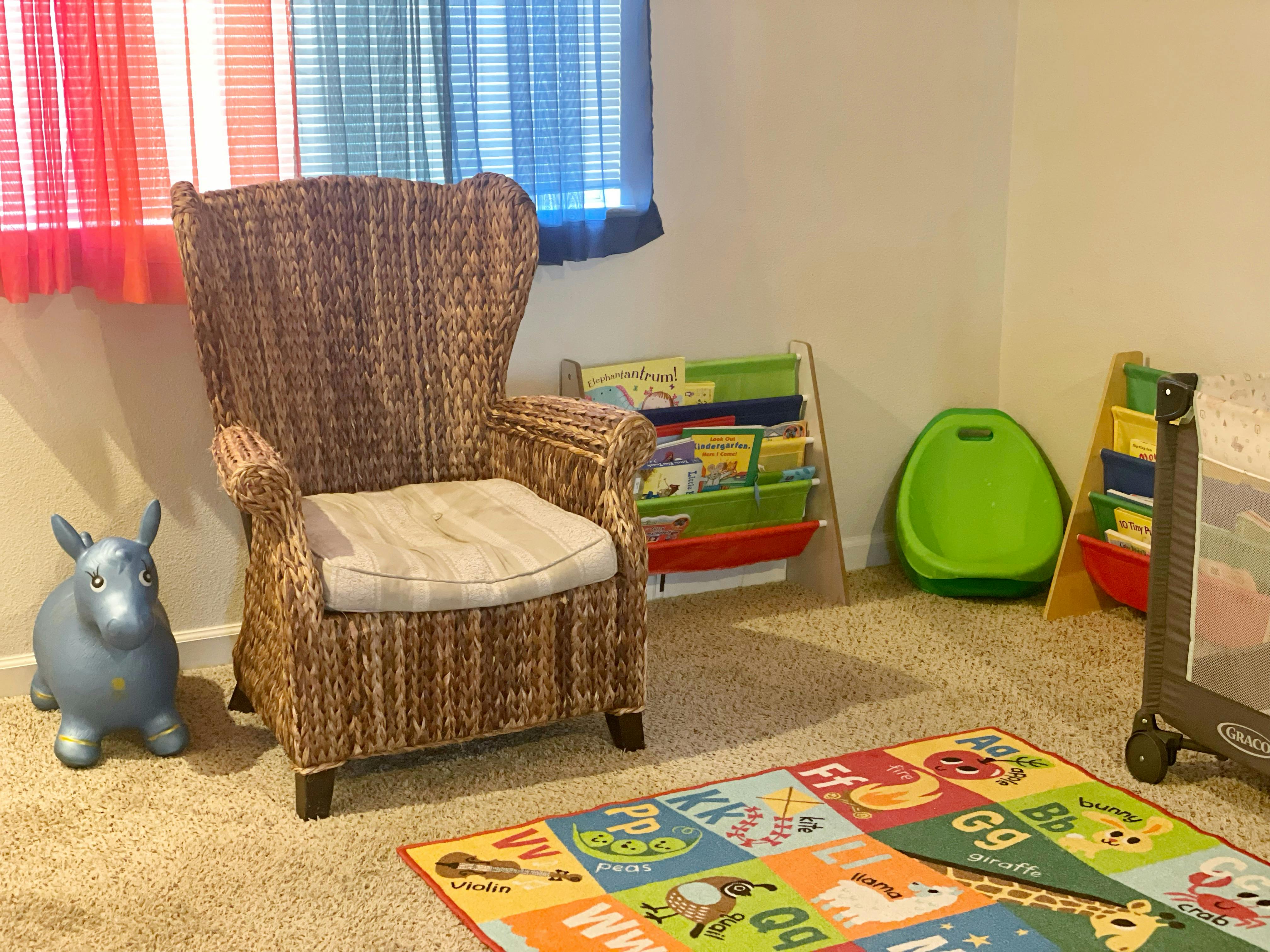 Wicker chair with a cushion, toy animal, and colorful rug in a room