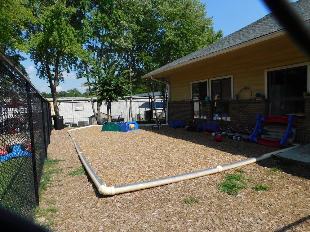 Outdoor play area with wood chips and a building