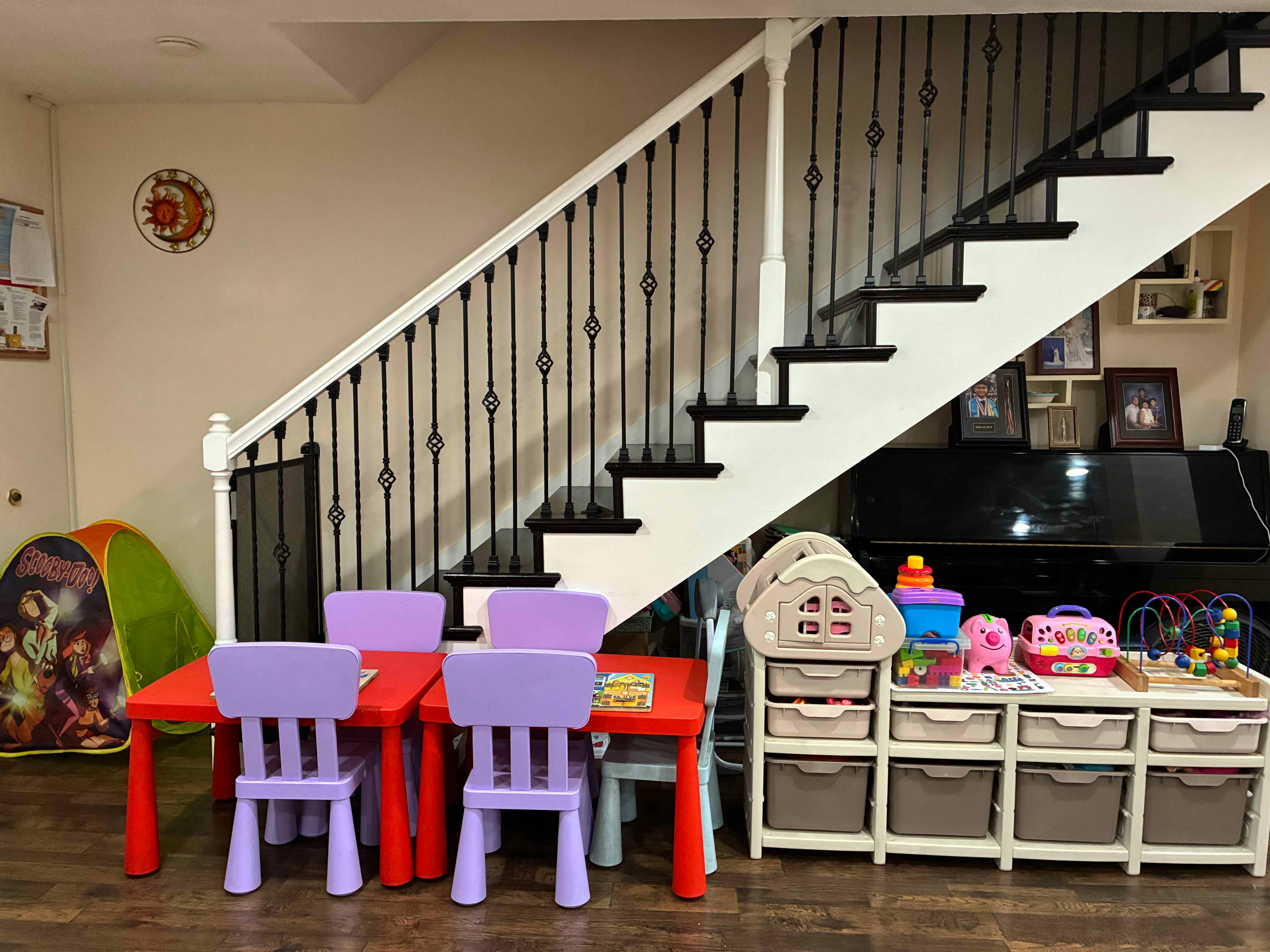 A children's play area with two red tables, purple chairs, and toy storage units