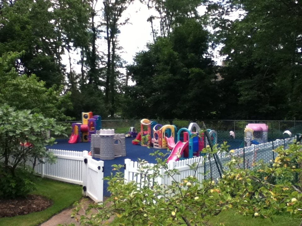 Playground with colorful slides and play structures on blue ground, fenced area