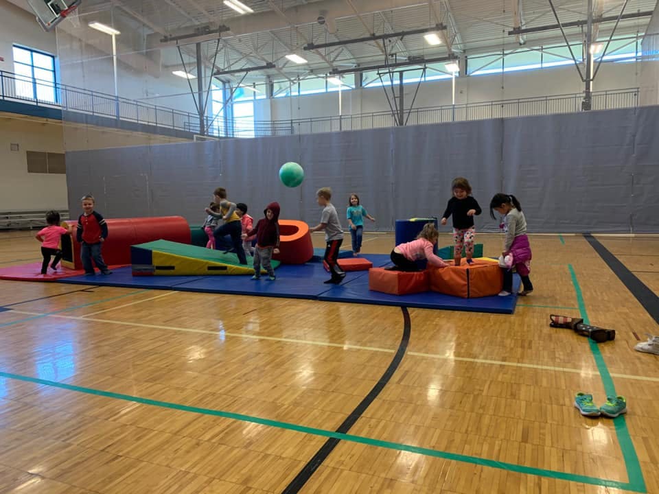 Children playing with soft blocks and a ball in a gymnasium