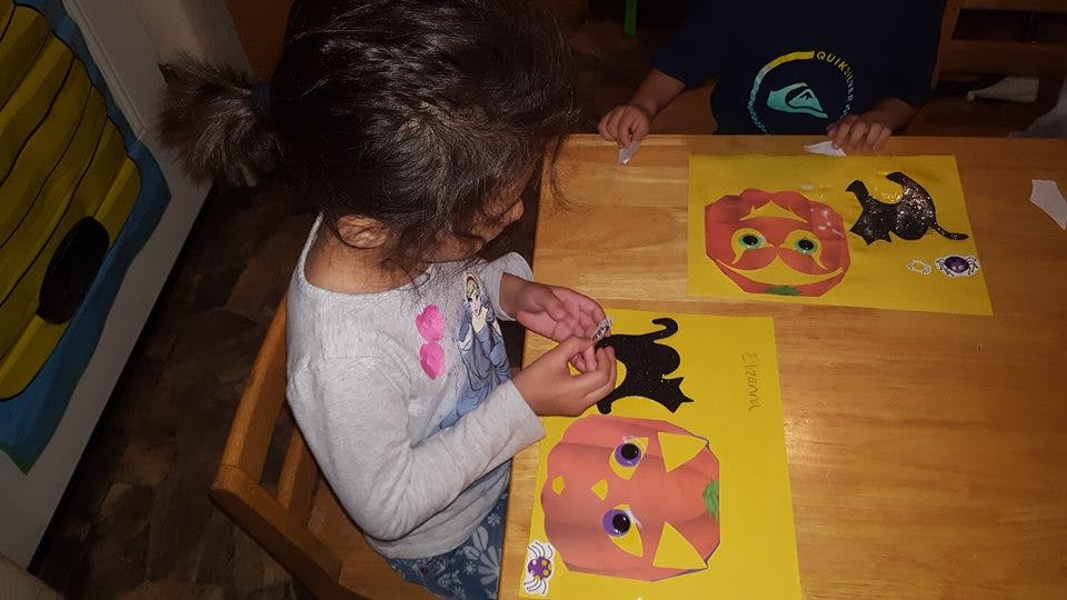Child making a craft with paper cutouts on a table
