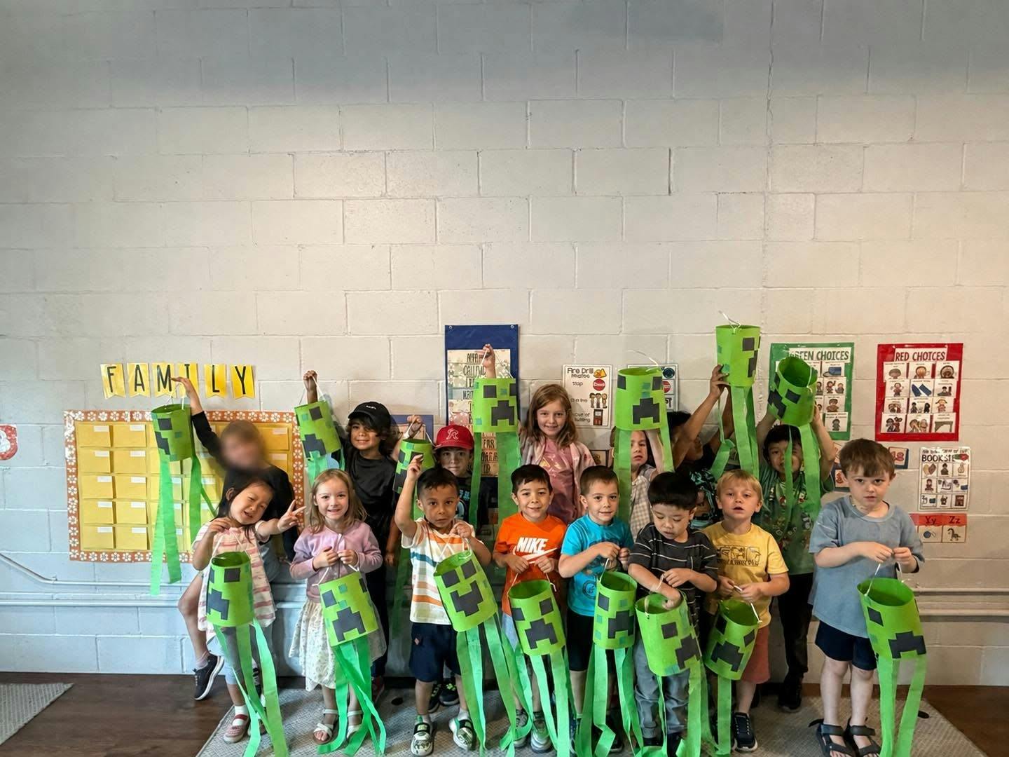 Group of children holding green paper crafts in a classroom