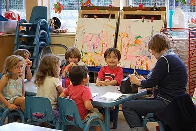 Adult and children sitting at a table in a classroom