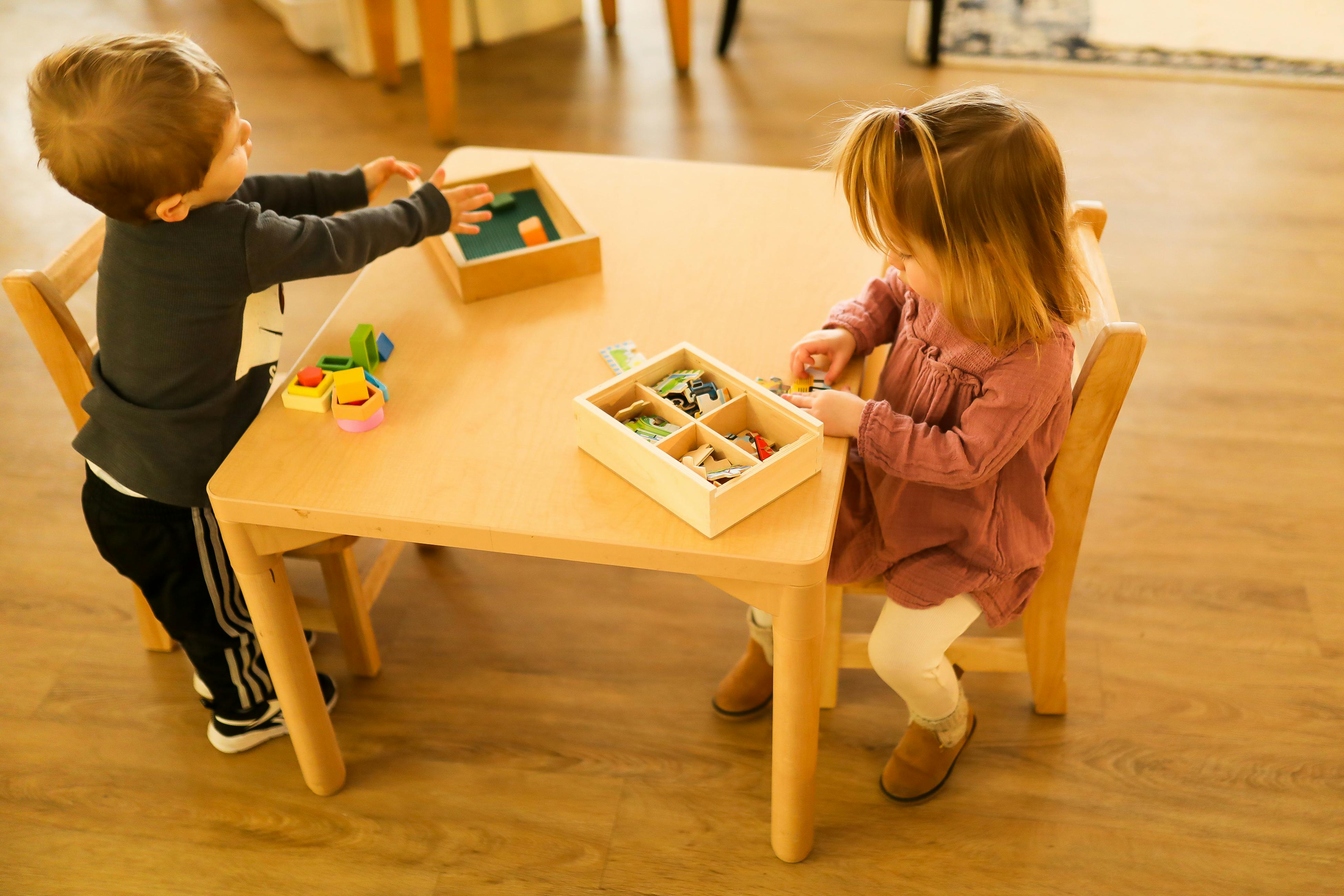 Two children playing with toys at a small table