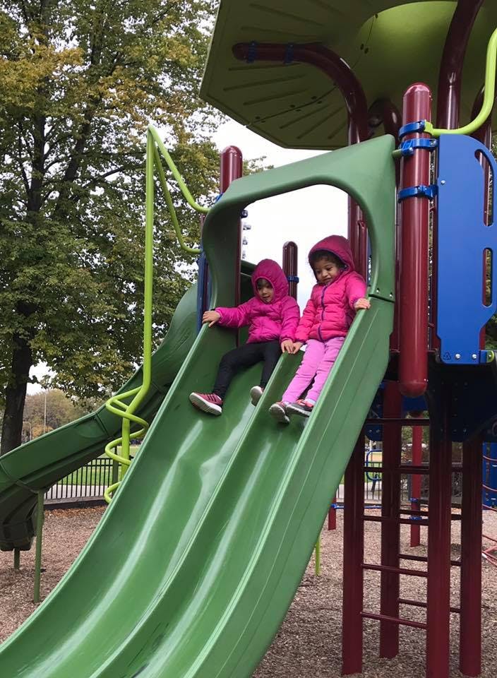 Two children on a green playground slide