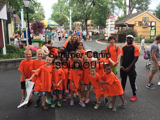 Adults and children in orange shirts posing for a group photo