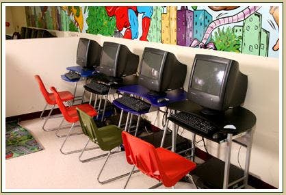 Row of computer workstations with monitors, keyboards, and chairs