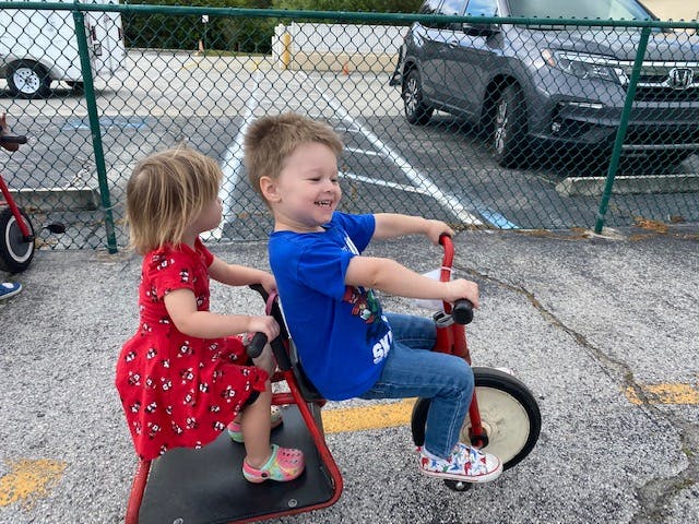 Two children riding a tandem tricycle