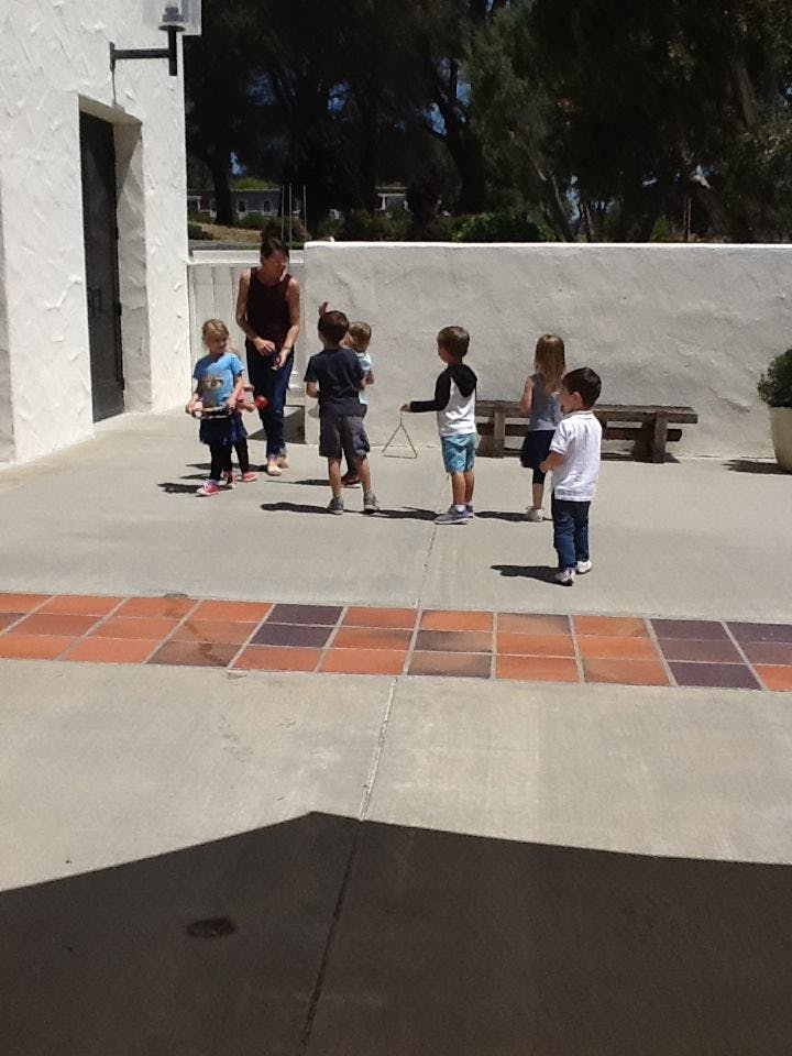 Adult and multiple children standing on a paved area