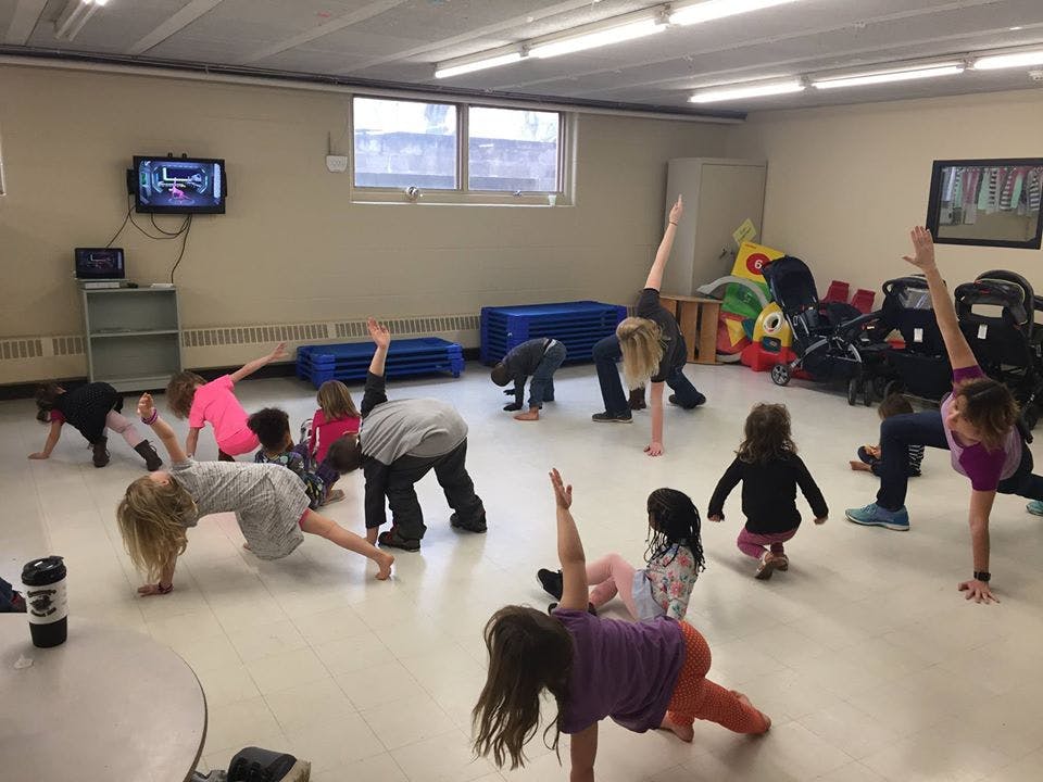 Children and adults doing yoga poses in a room
