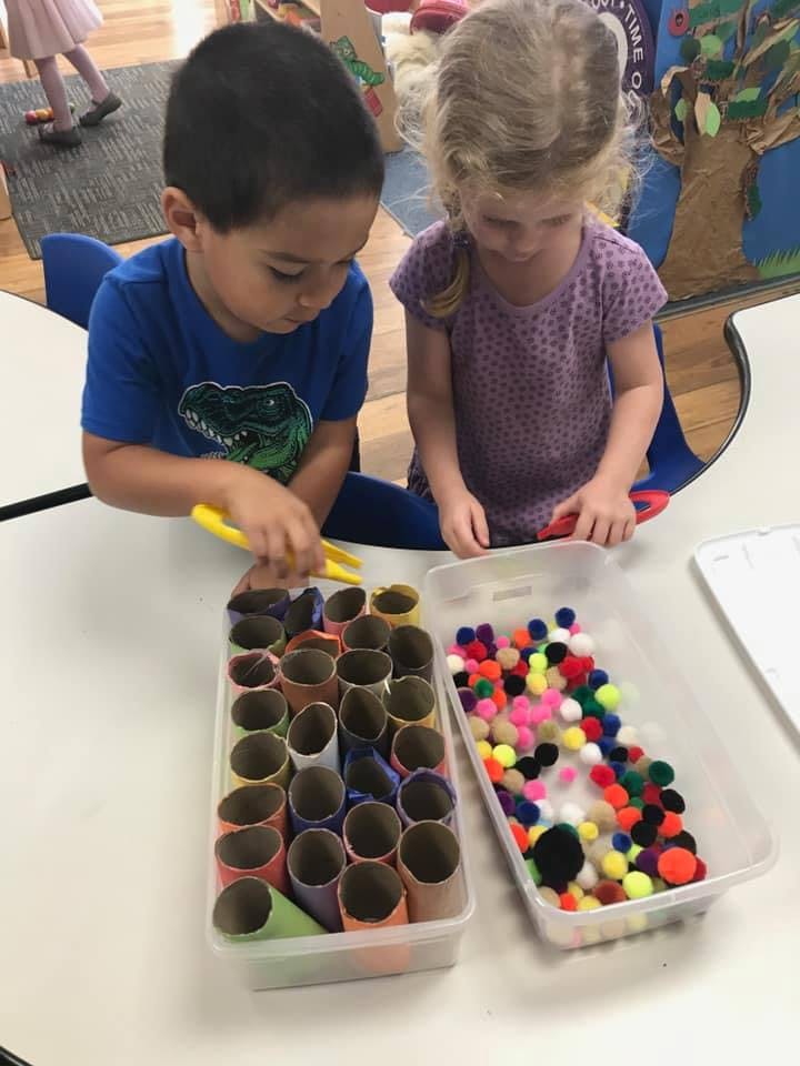 Two children playing with craft supplies at a table