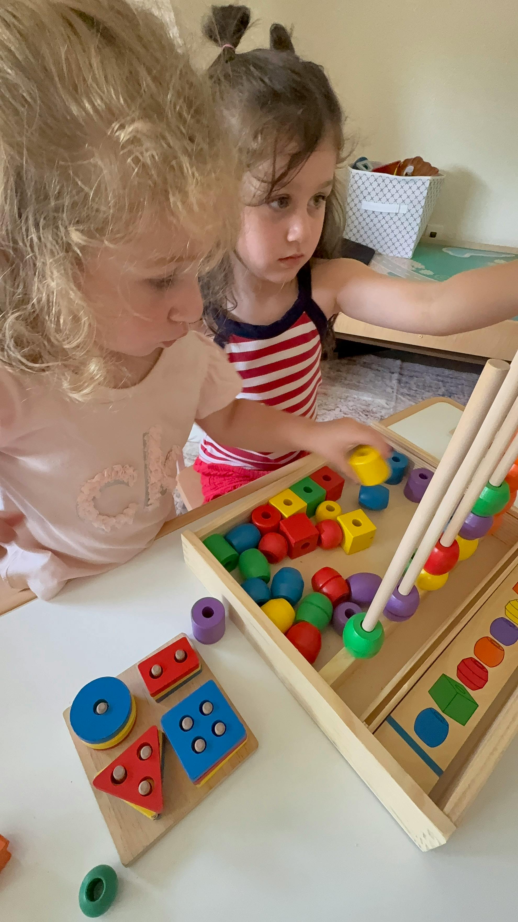 Two children playing with colorful wooden shape sorter toys