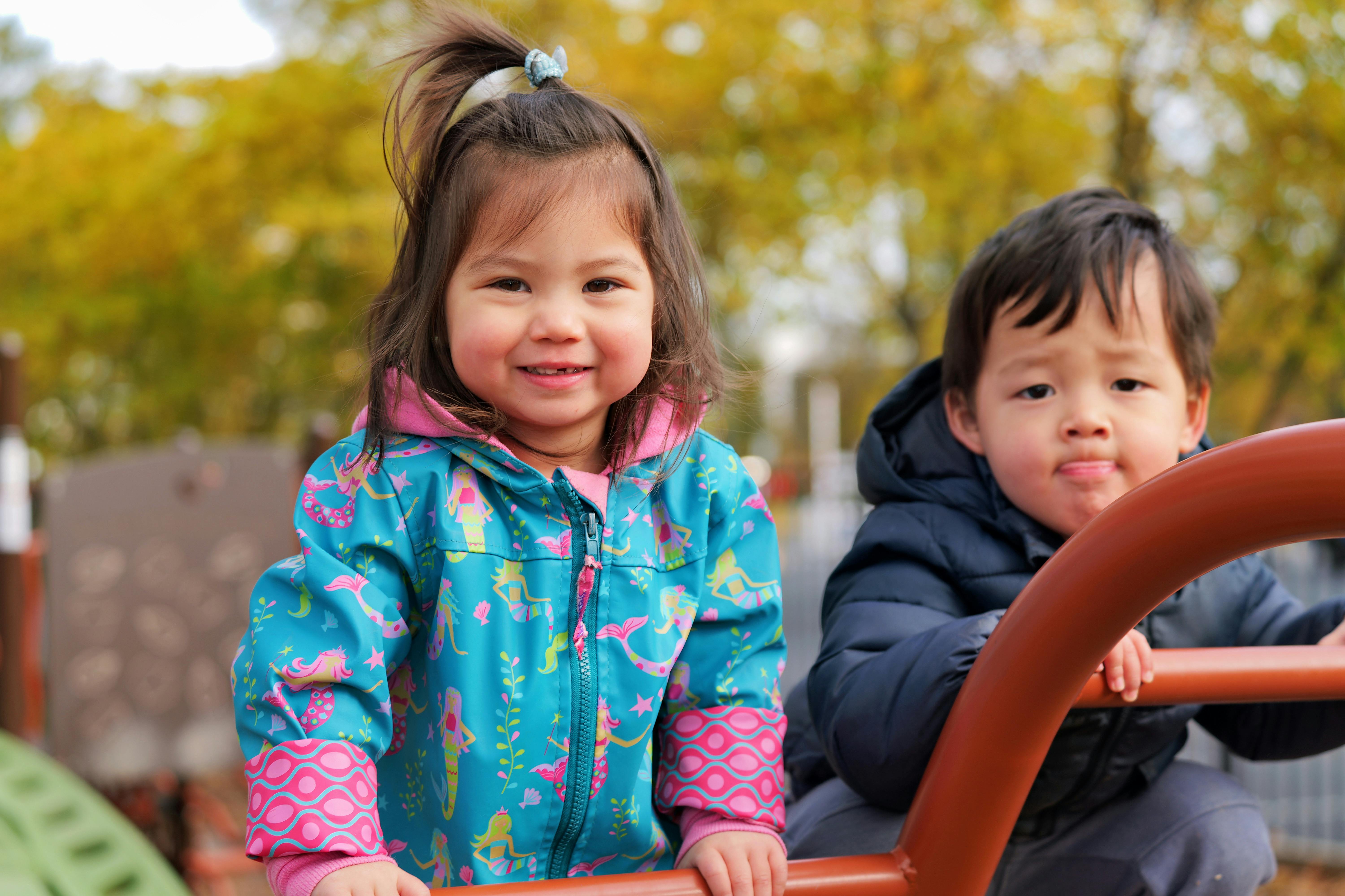 Two children playing on playground equipment outdoors