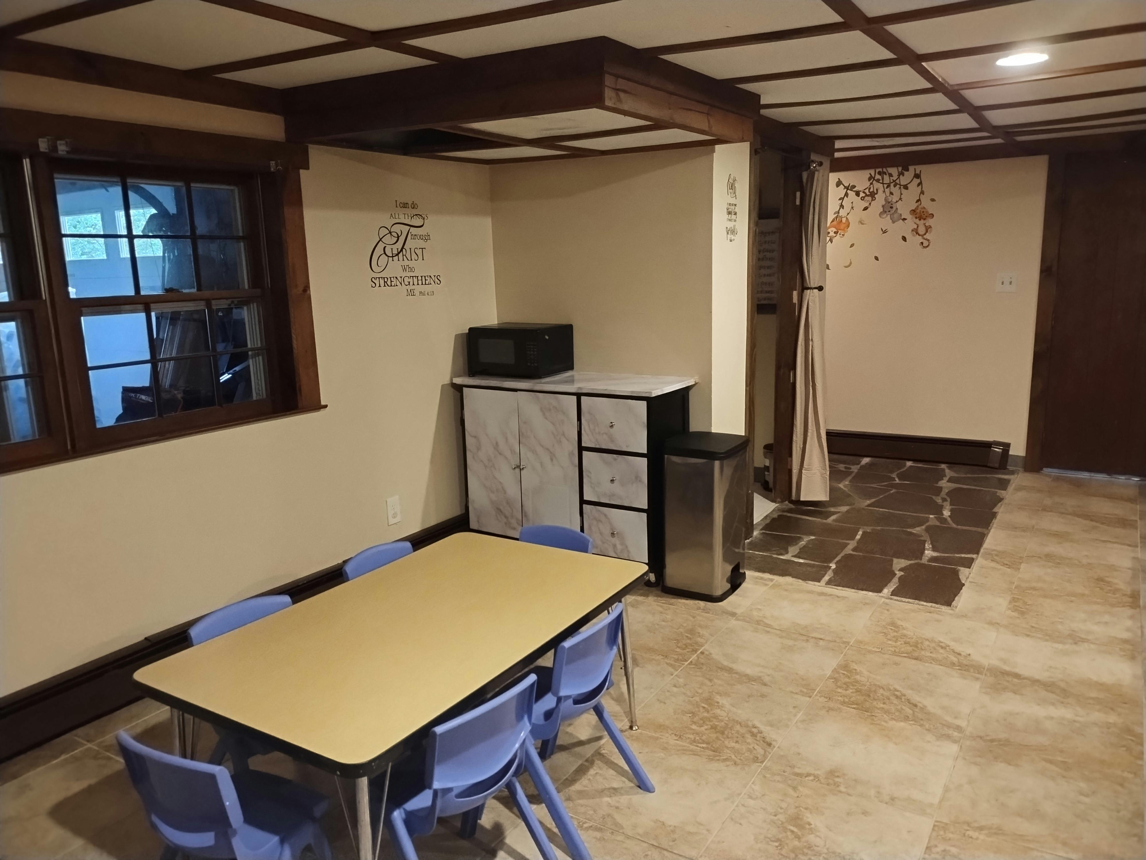 Table with chairs in a room with a window and microwave