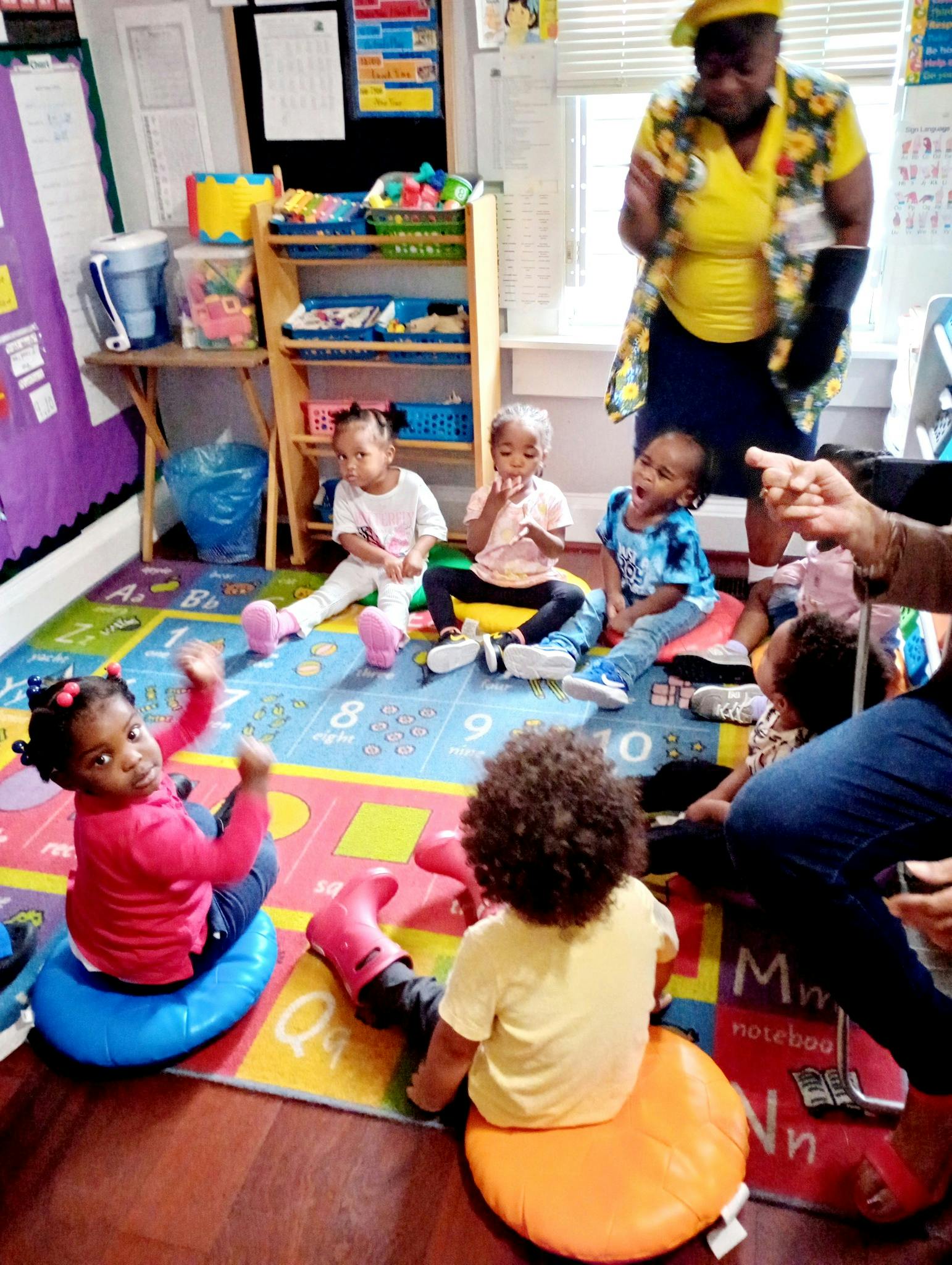 Adult and children sitting on floor cushions in a classroom