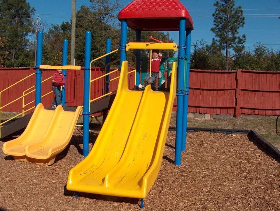 Two children on a playground structure with yellow slides