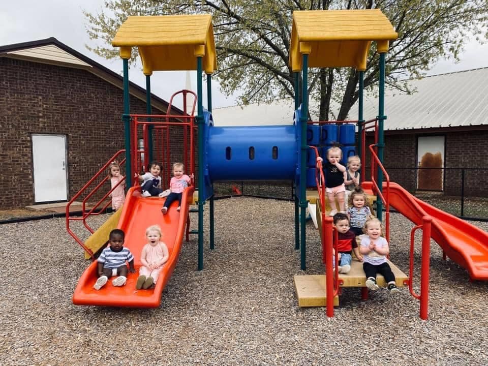 Children on a playground structure with slides and a tunnel