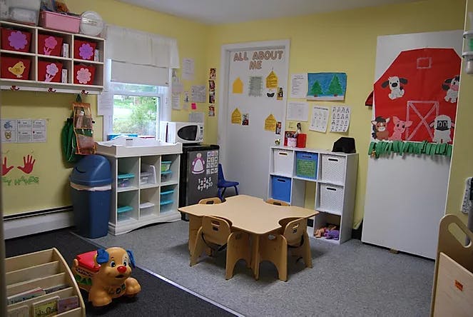 Child's classroom with small table and chairs, storage shelves, and decorations