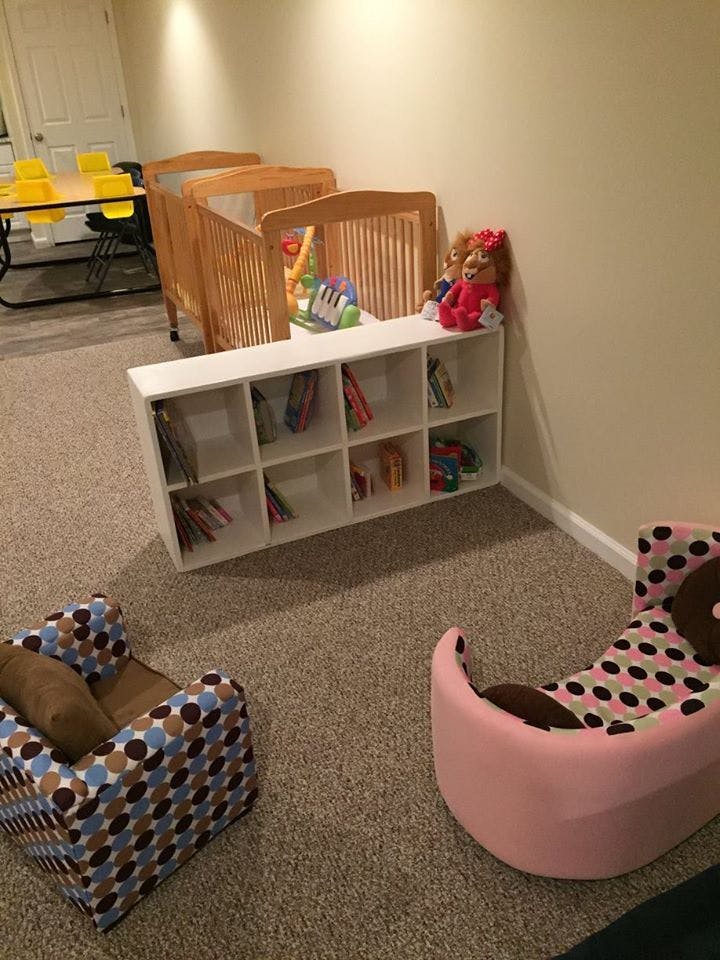 Cribs, a bookshelf with toys, and small chairs in a room