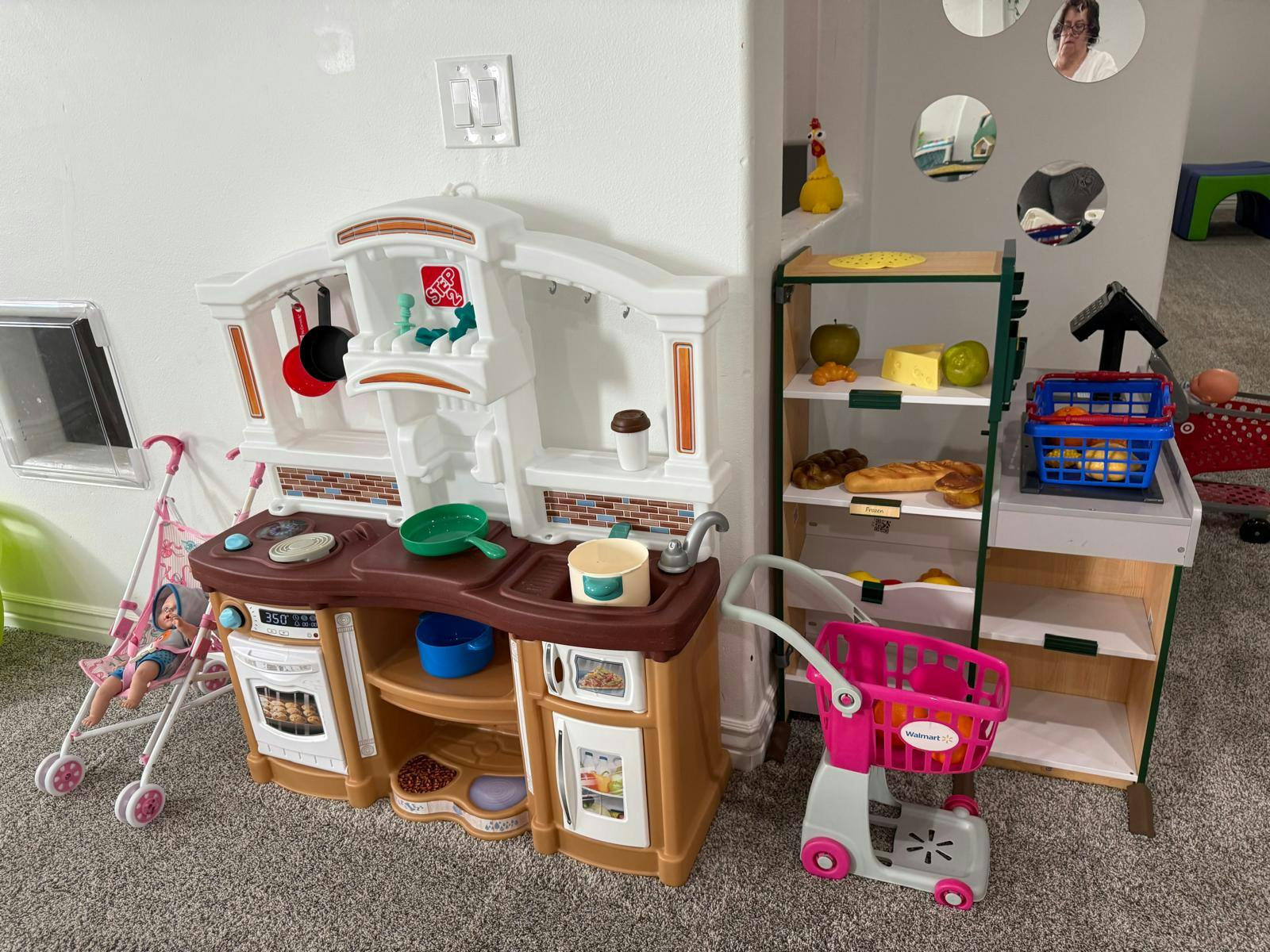 Play kitchen and grocery store setup with toy food and shopping cart