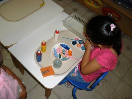 Child painting at a small table with various art supplies