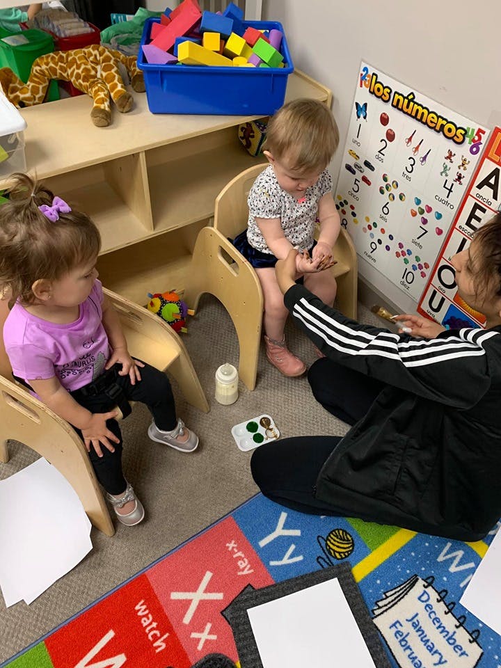 Adult interacting with two children in a play area