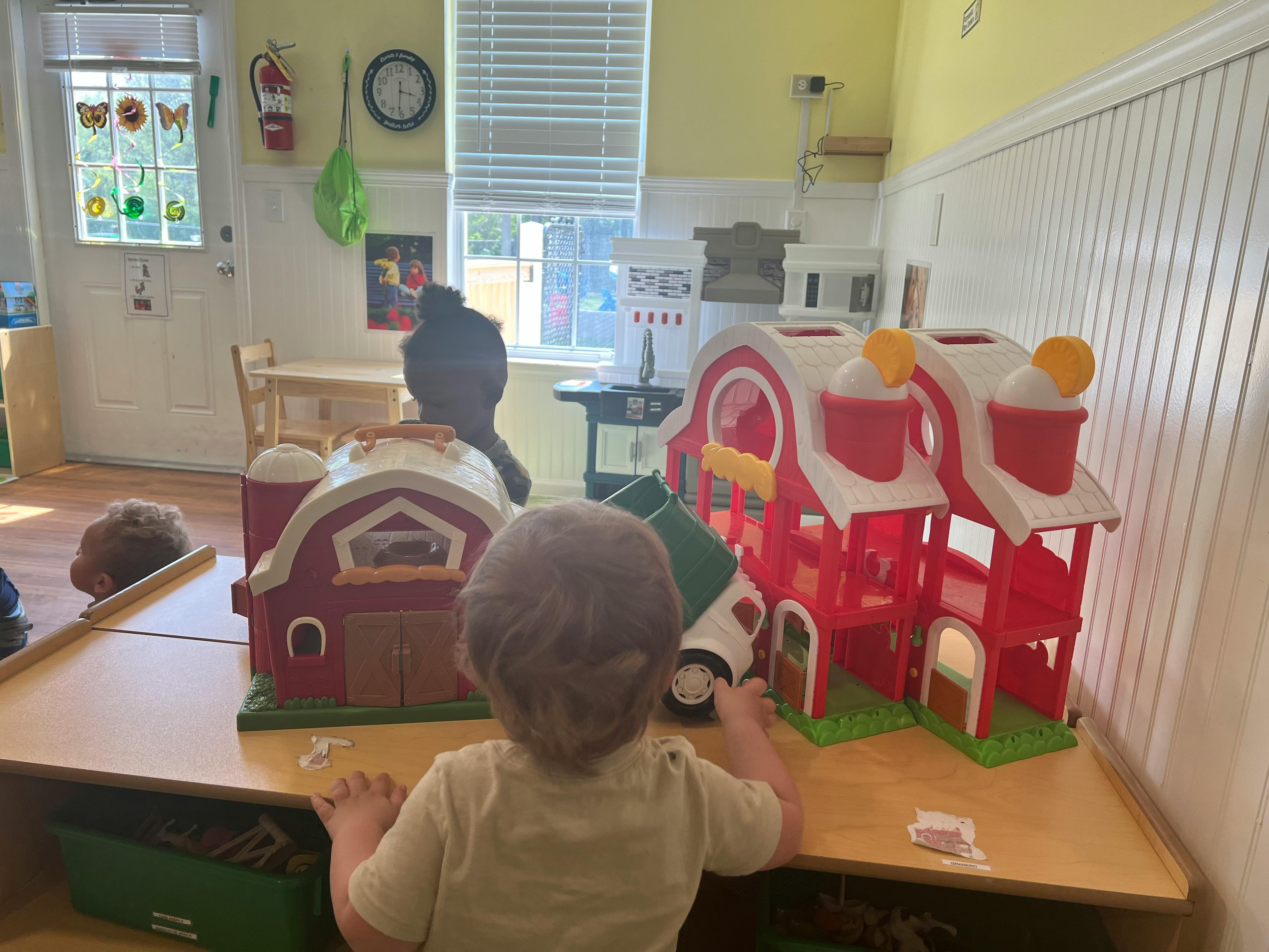 Child playing with toy barns in a classroom