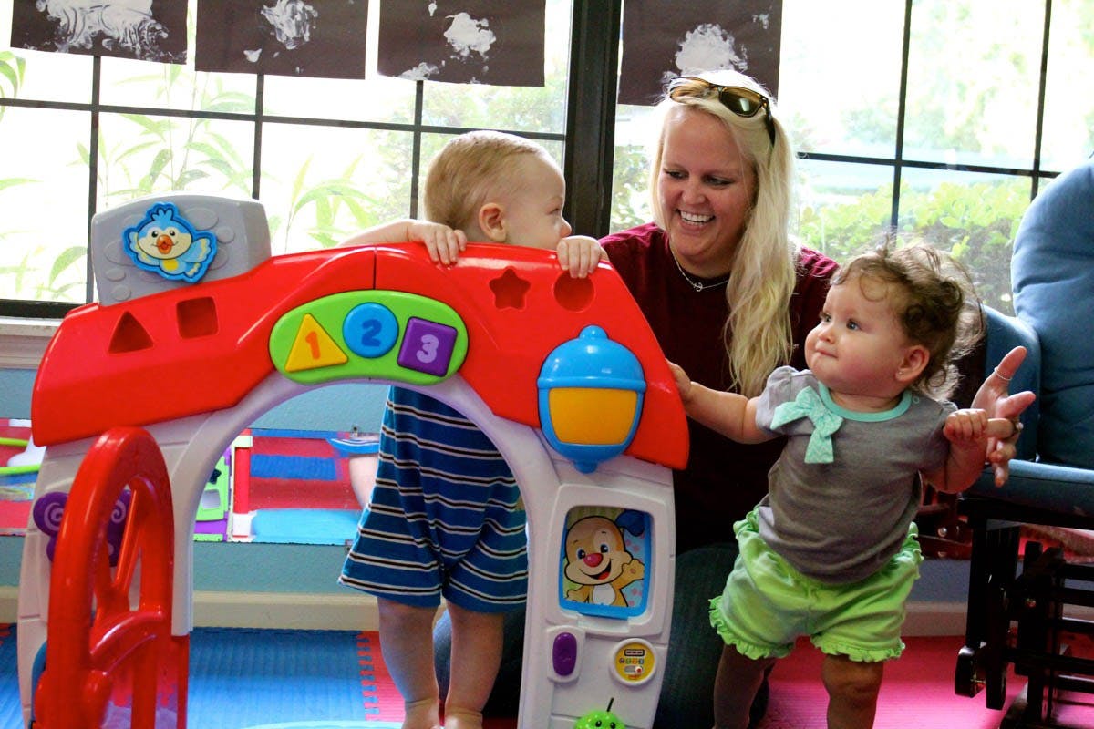 Adult and two children playing with a toy house