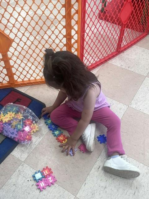 Child sitting on floor playing with interlocking number puzzle pieces