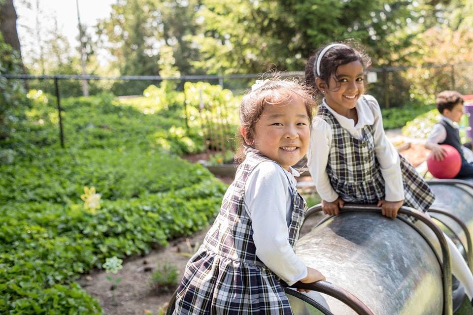 Two children in plaid dresses on a playground structure