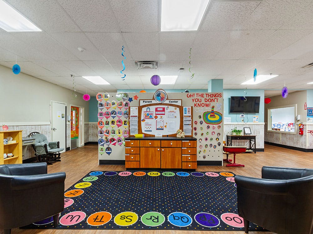 Childcare waiting room with an alphabet rug and parent information