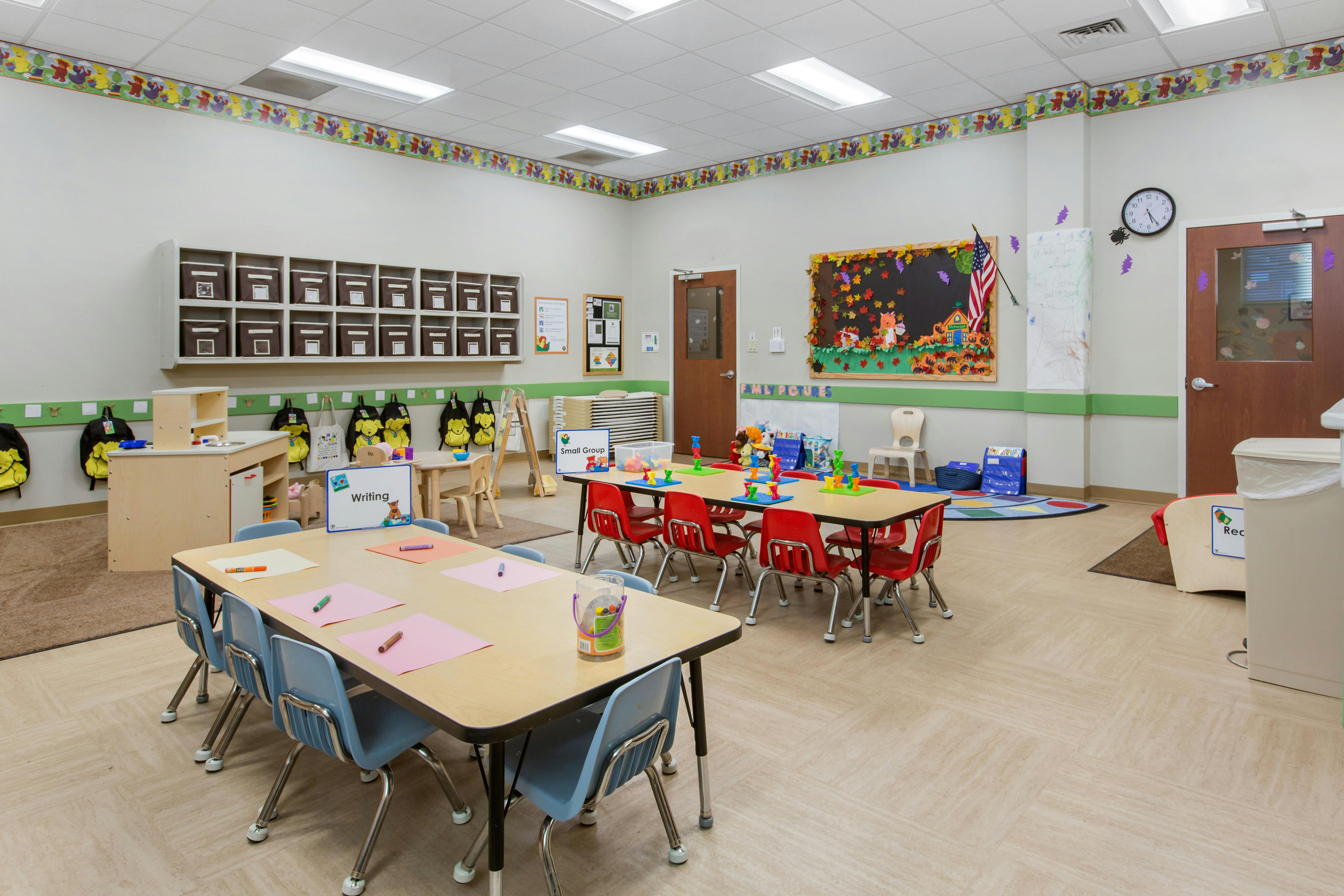 An empty early childhood classroom with multiple tables and chairs arranged