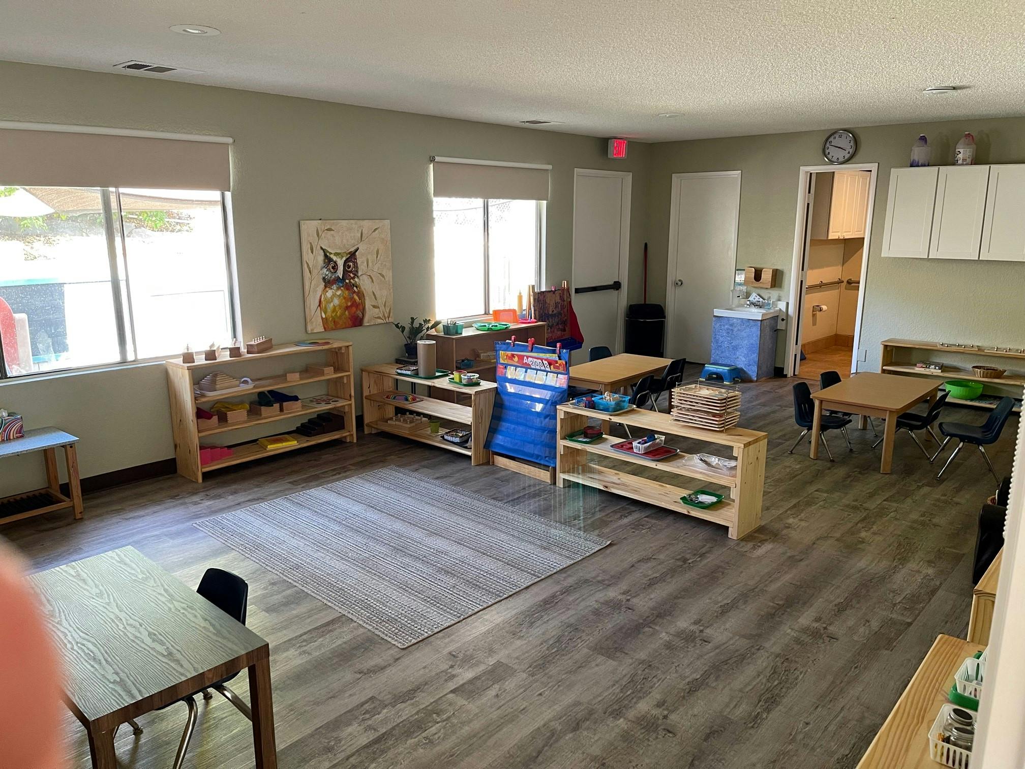 Classroom with tables, shelves, and a rug on the floor
