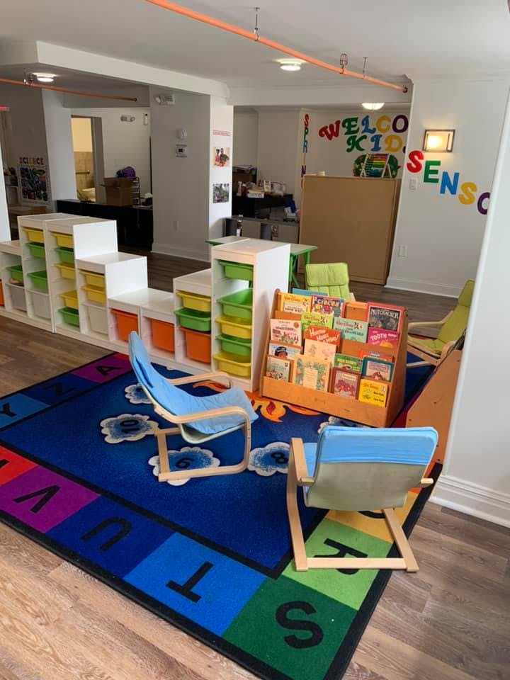 Children's play area with a colorful rug, chairs, and storage shelves