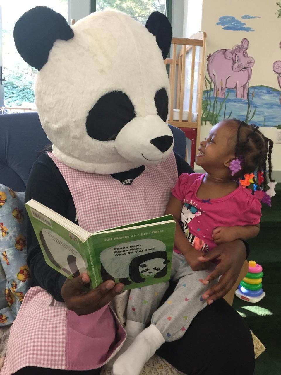 Person in panda costume reading a book to a child
