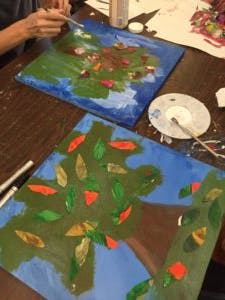 Person painting a tree on a canvas