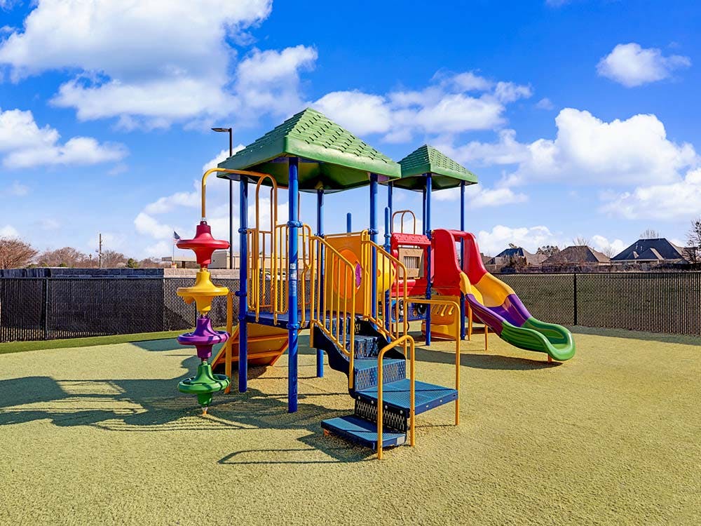 Colorful playground structure with slides and climbing elements on a green artificial turf