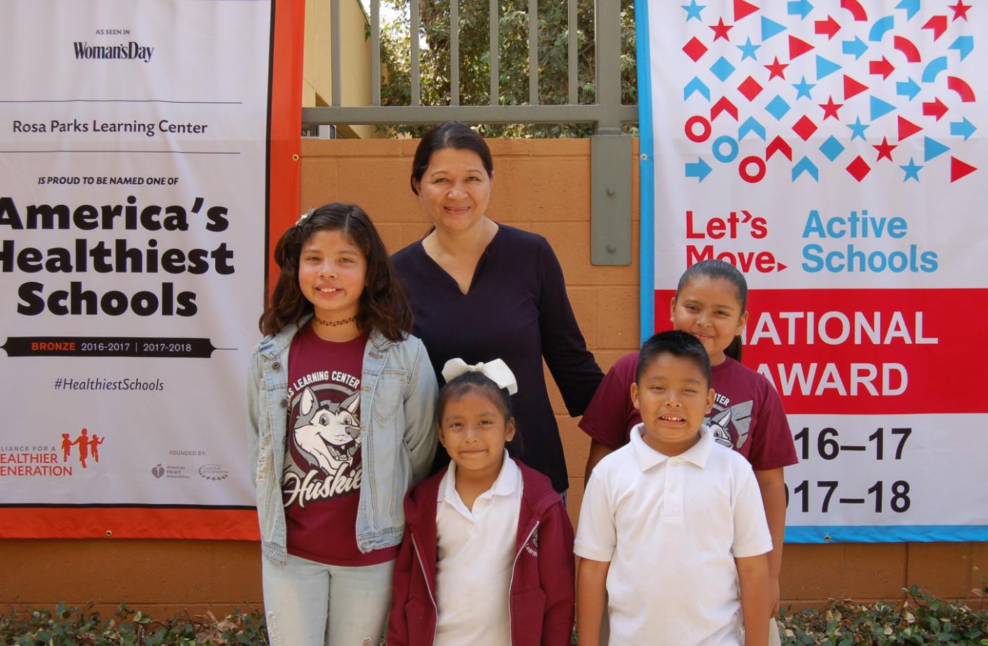 Adult and four children standing in front of banners for "America's Healthiest Schools"
