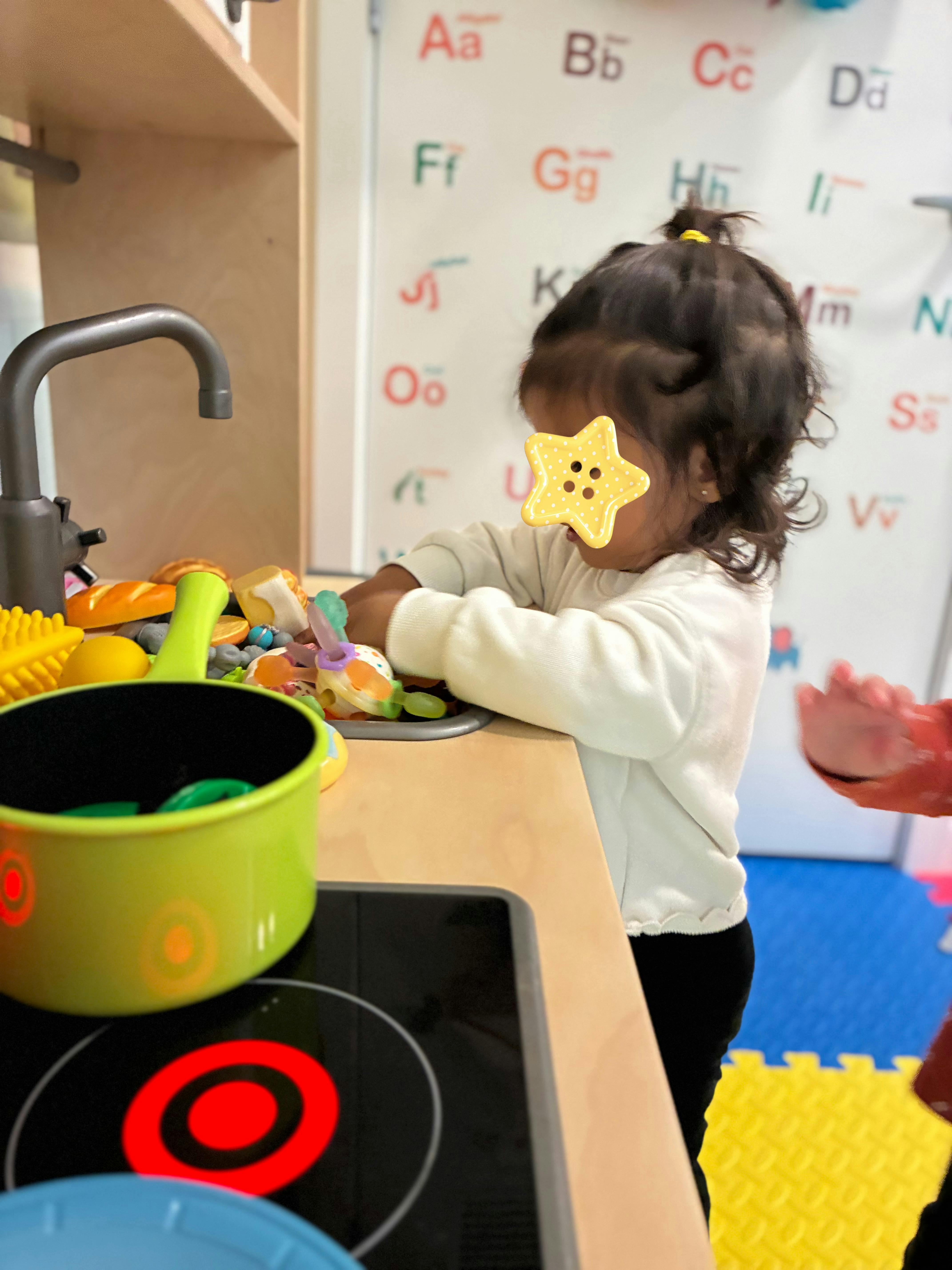 Child playing with a toy kitchen in a classroom