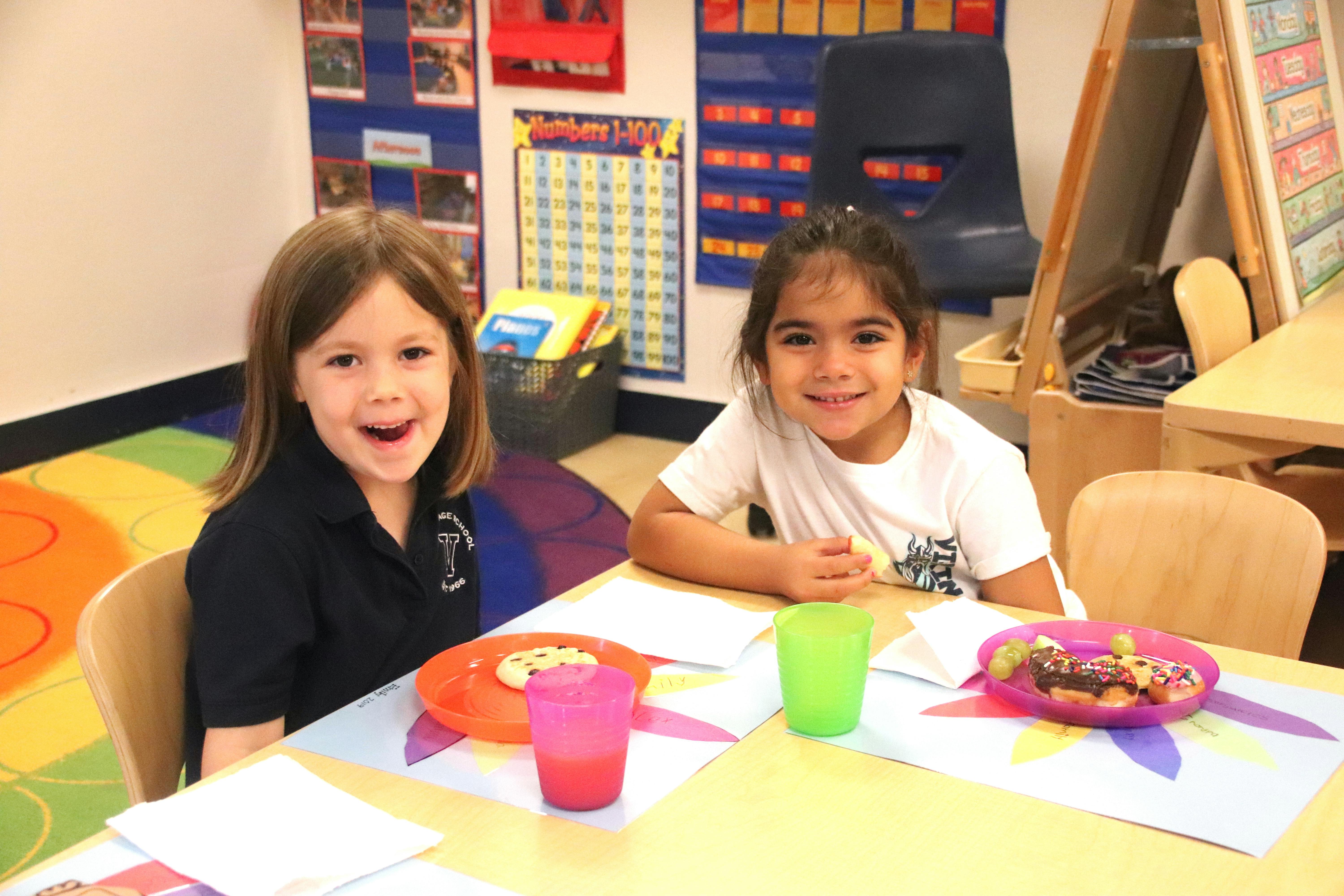 Two children sitting at a table with plates and cups