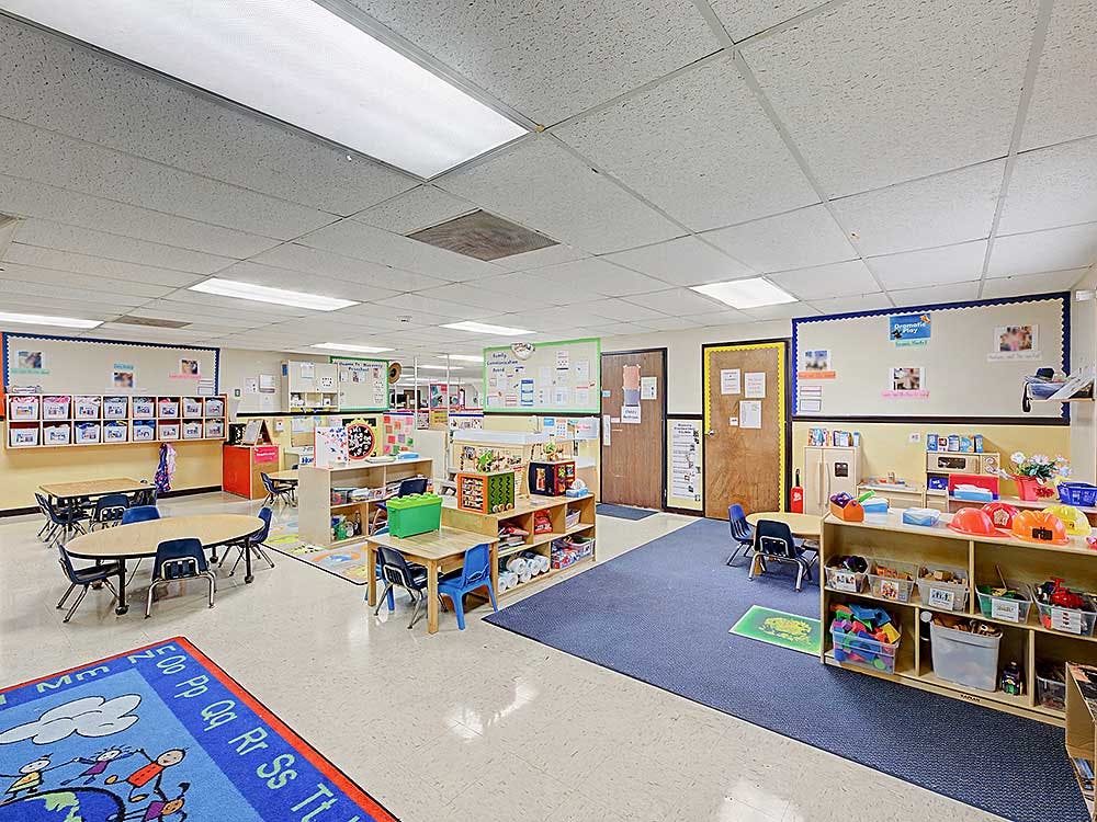 A colorful empty classroom with small tables and chairs