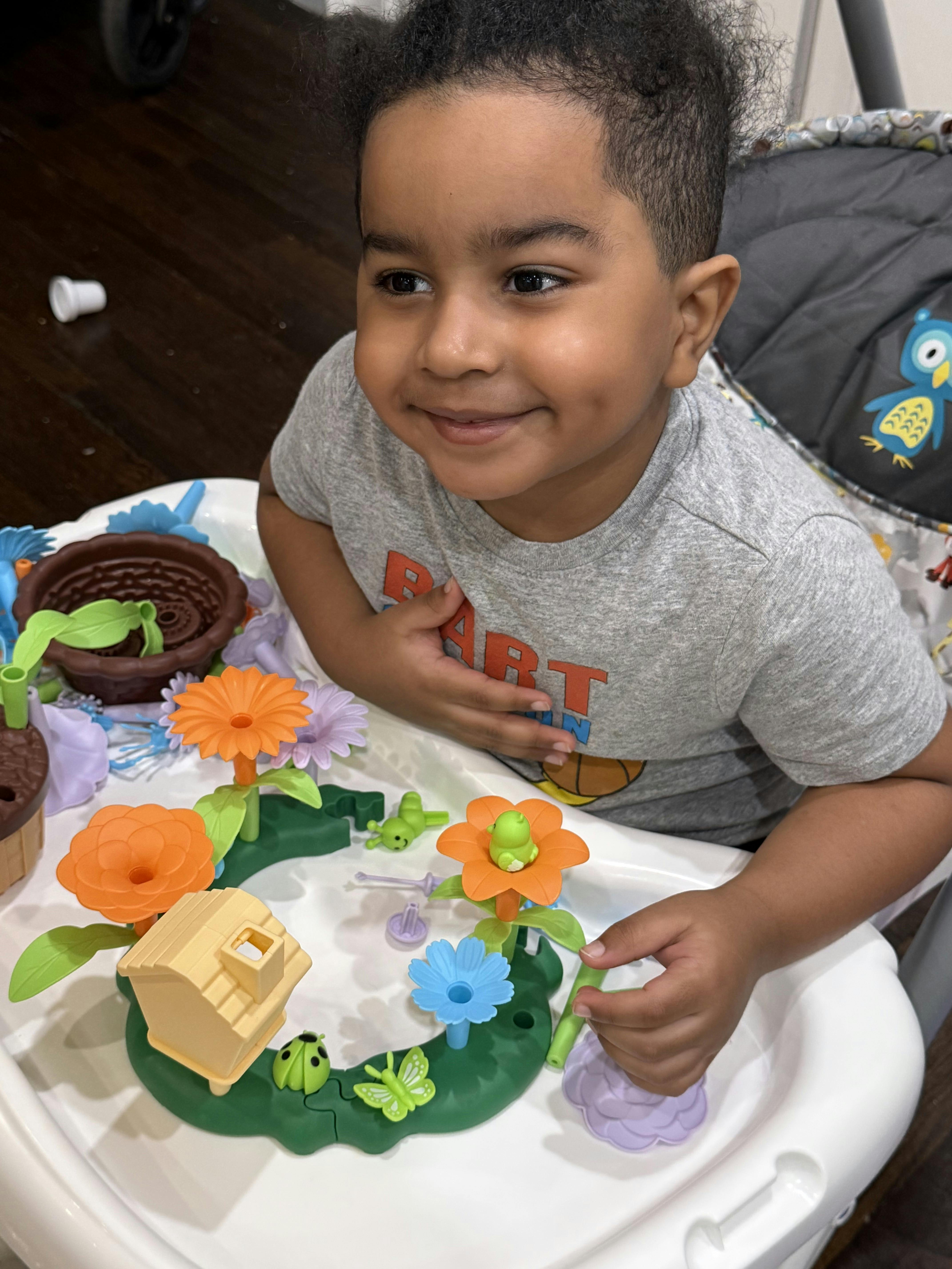 Child playing with a flower-themed toy on a high chair tray