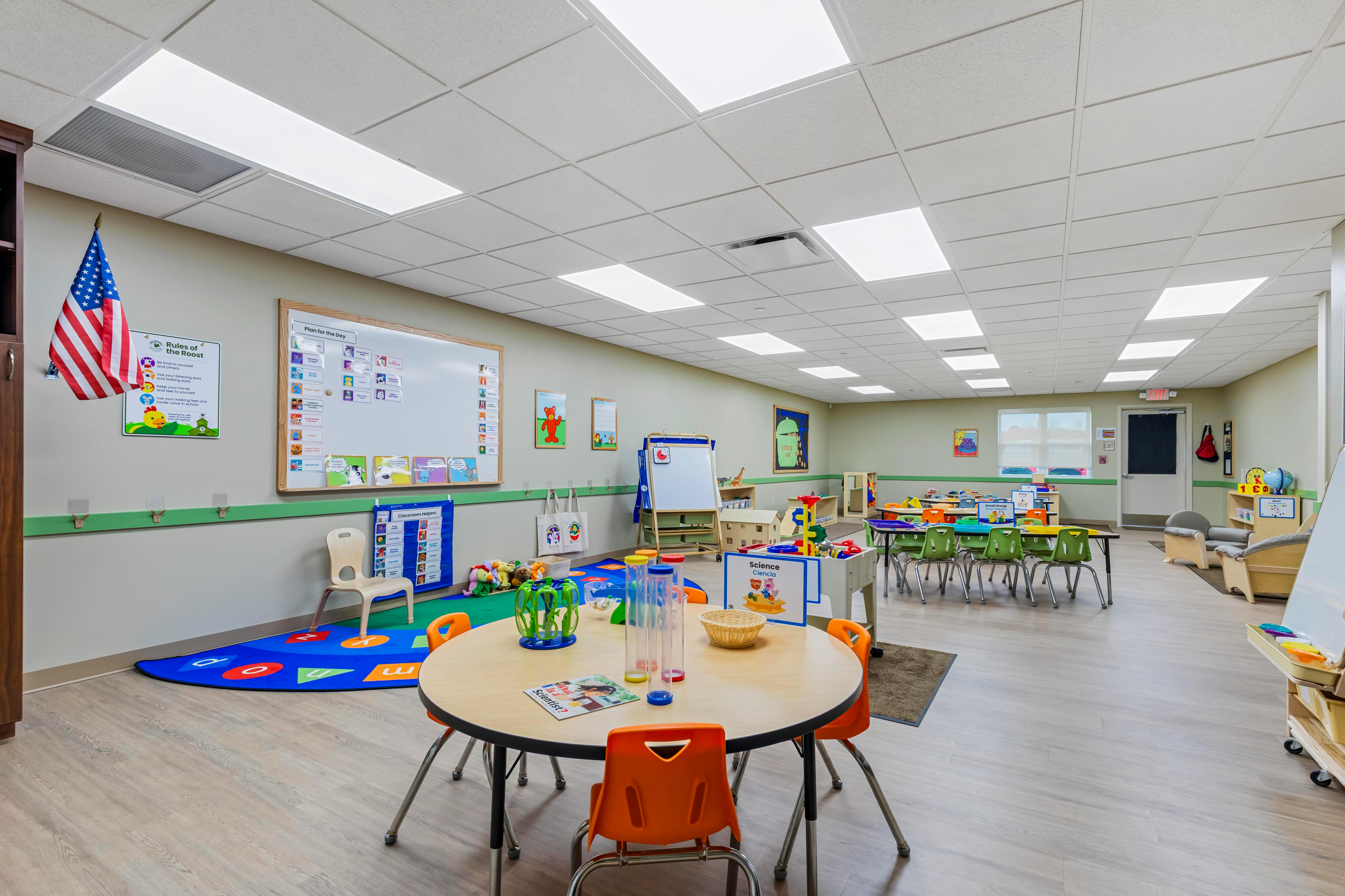 A colorful empty classroom with small tables, chairs, and learning materials