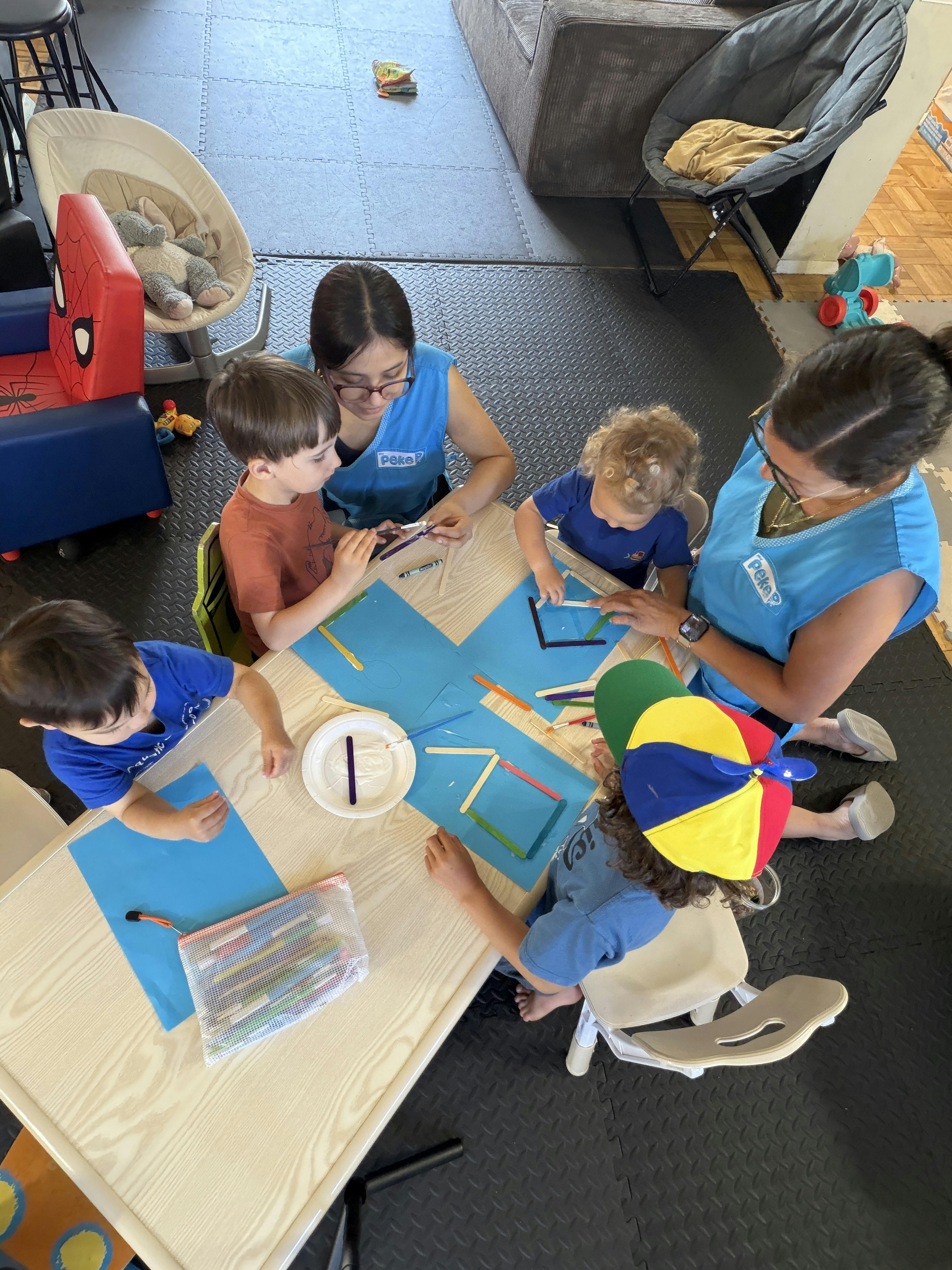 Adults and children doing a craft project with popsicle sticks at a table