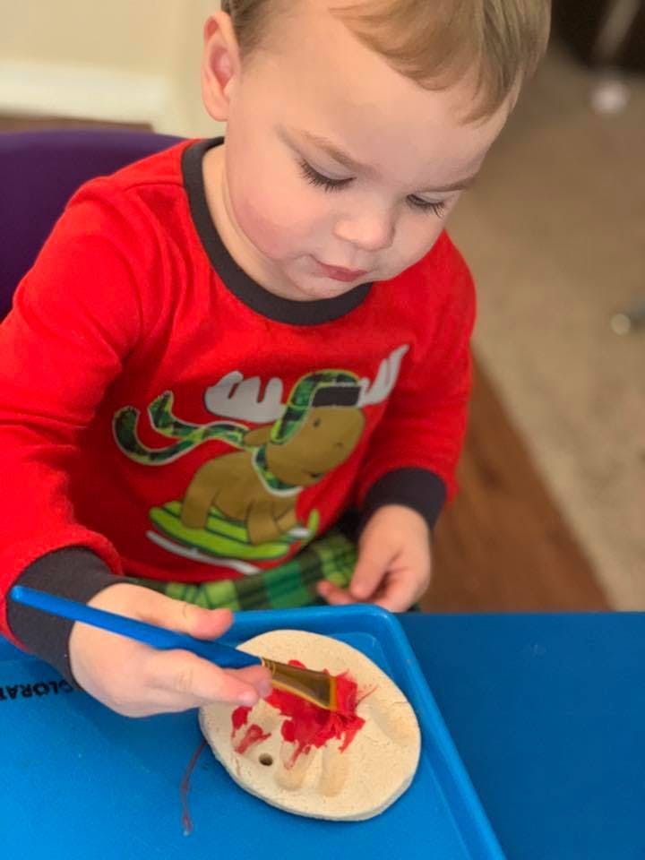 Child painting a craft with red paint
