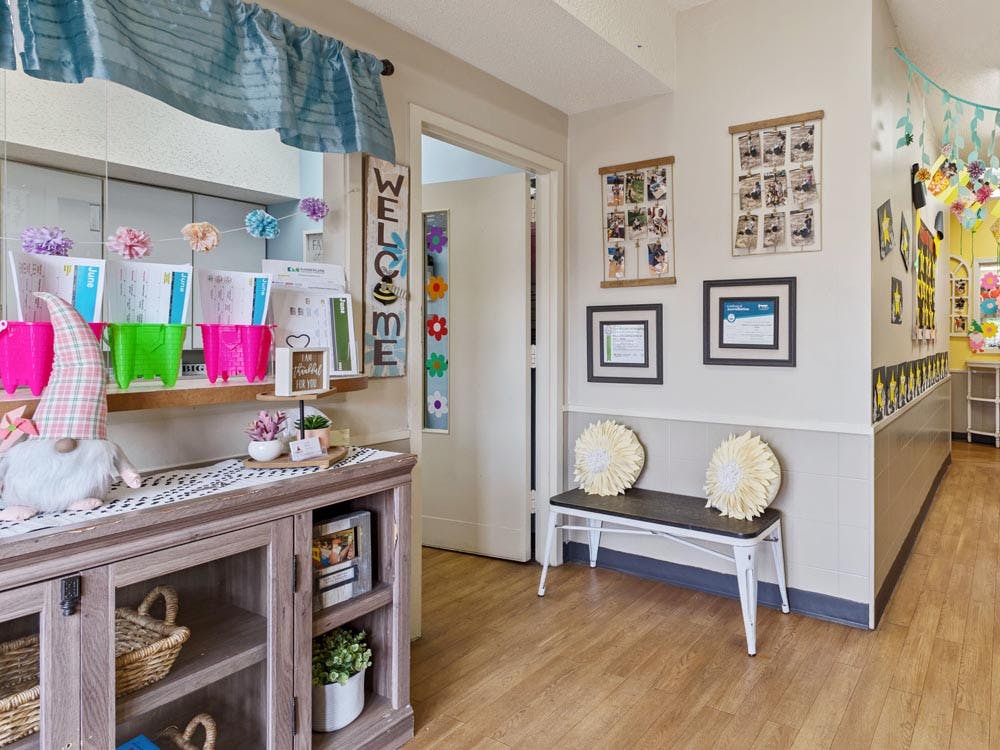 Hallway decorated with a welcome sign, children's art, and a storage cabinet
