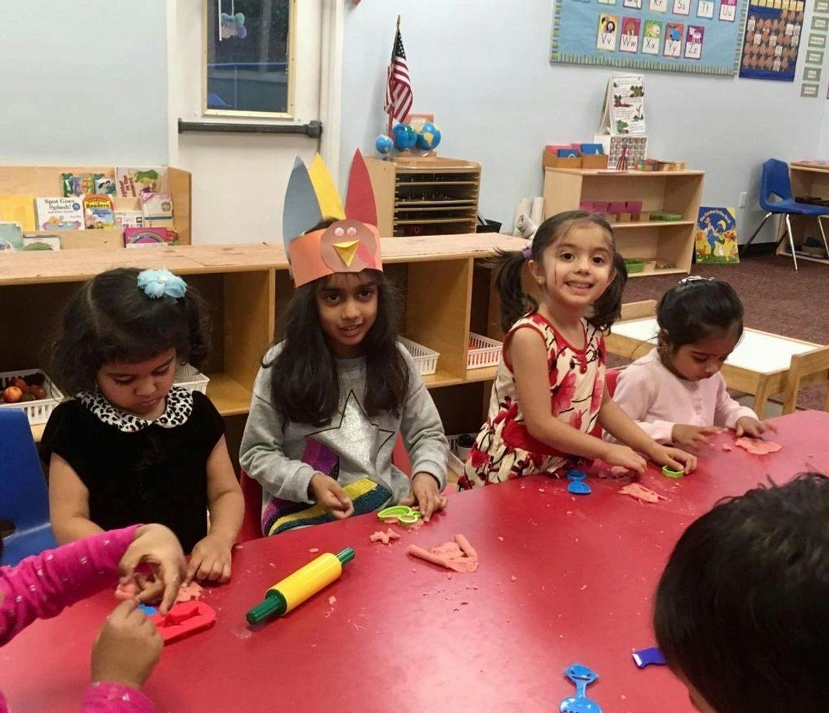 Children playing with modeling clay at a red table