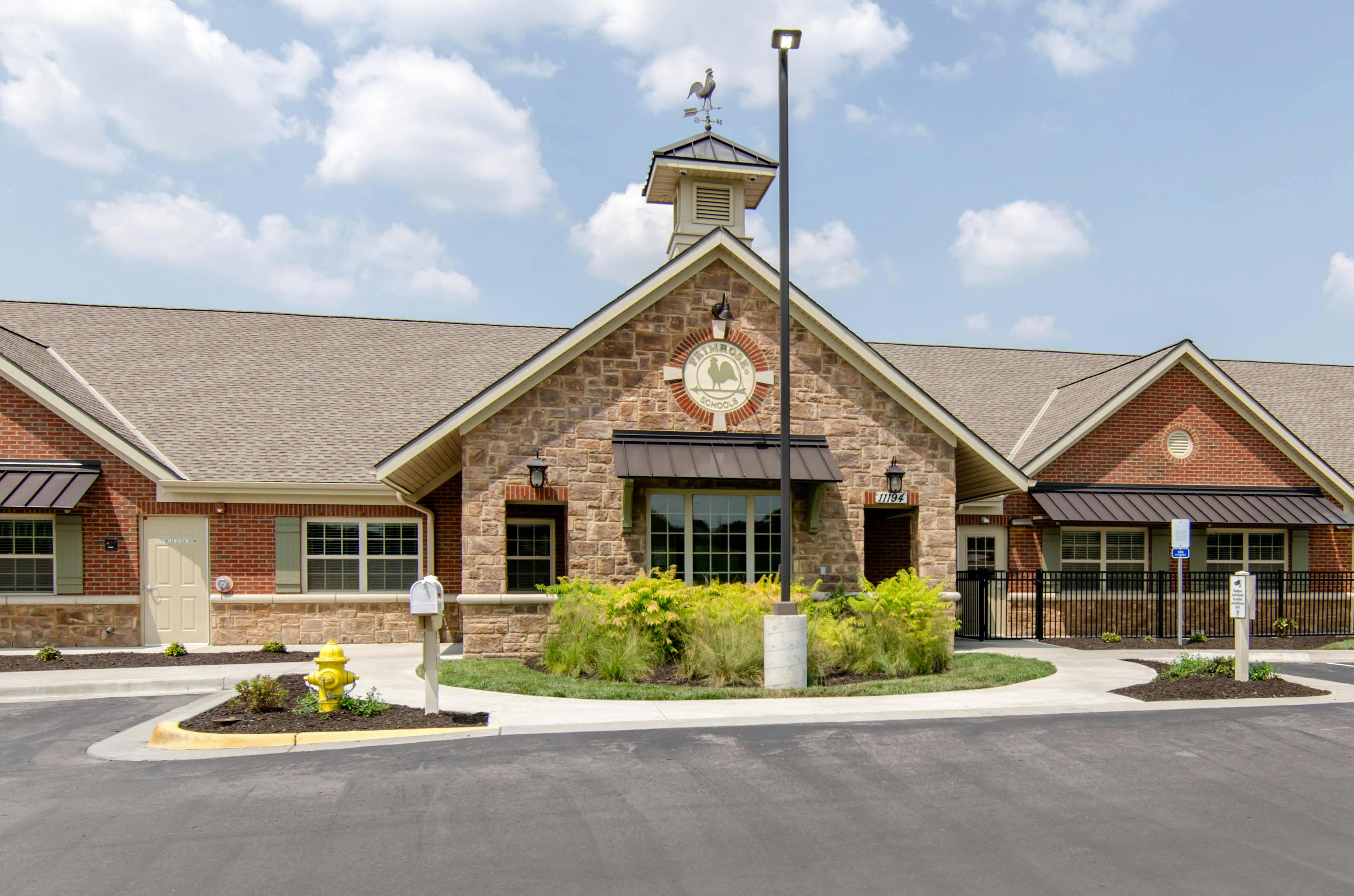Primrose Schools building exterior with stone and brick facade, cupola, and weather vane