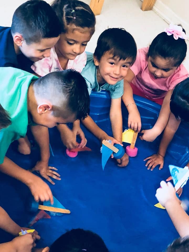 Children playing with small boats in a blue tub